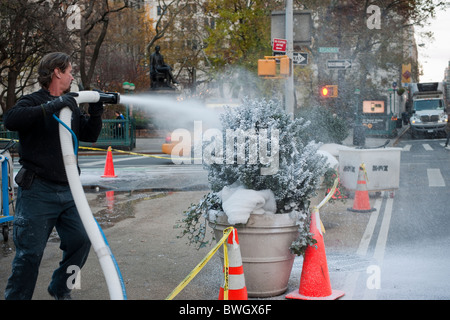 Workers spray faux snow onto plantings in Madison Square in New York for the filming of  the 'Mr. Popper's Penguins' movie Stock Photo