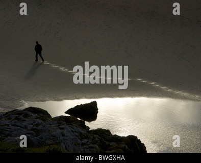 Man walking across beach Stock Photo