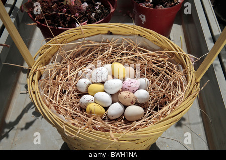 Small chocolate easter mini eggs on straw in a straw basket. Stock Photo