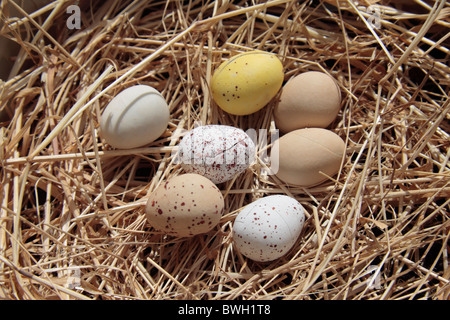 Small chocolate easter mini eggs on straw in a straw basket. Stock Photo