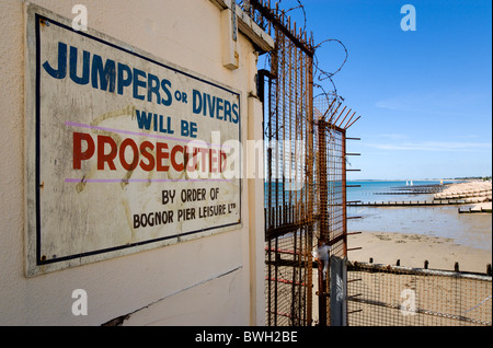England West Sussex Bognor Regis Warning sign against jumping or diving off pier into water on pier with beach beyond Stock Photo