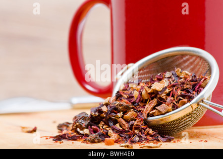 Dried fruit tea in tea strainer with cup of tea Stock Photo
