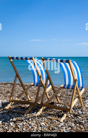 England, West Sussex, Bognor Regis, Two blue and white deck chairs on the shingle pebble beach looking out to sea.