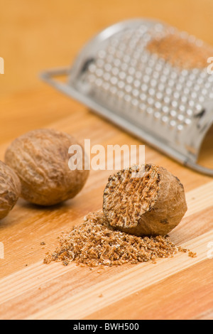 Whole and grind nutmeg with grinder over wood background Stock Photo