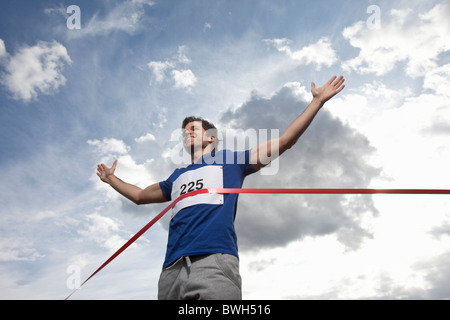 Young man crossing finish line Stock Photo