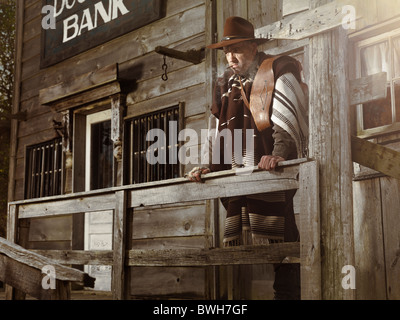 License and prints at MaximImages.com - Cowboy standing at a door in outside of a bank building at night Wild west villain notorious criminal robber Stock Photo