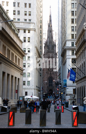 USA New York NYC Manhattan Gothic Trinity Church with people walking in Wall Street by security barriers Stock Photo