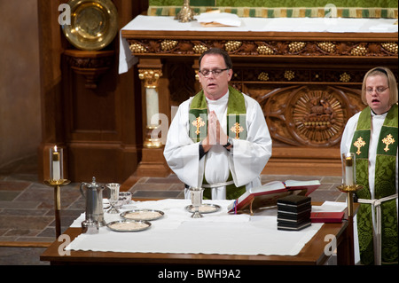 Anglo male presiding minister blesses communion table before congregational communion during Lutheran church service Stock Photo