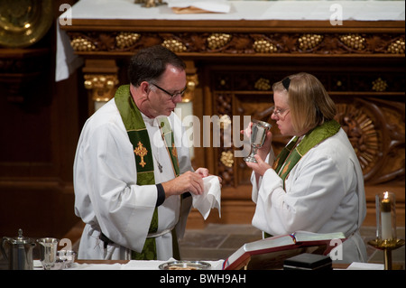 Anglo male presiding minister and Anglo female assisting minister share communion before congregational communion during service Stock Photo