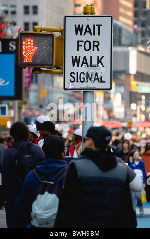 USA, New York, Manhattan, People in Times Square by pedestrian crossing sign with a red hand illuminated to stop Stock Photo