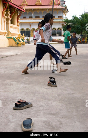 Children are playing a traditional street game with slippers at a Buddhist temple in Vientiane, Laos. Stock Photo