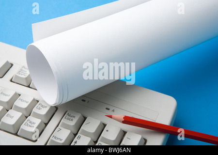 Close-up of red pencil, folded paper and part of keyboard on blue surface Stock Photo