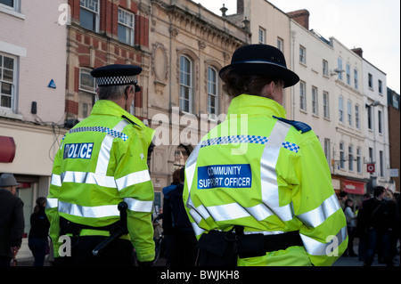 Woman police community support officer walking through Hereford City Centre, UK. Rear view of female CSO with male colleague.