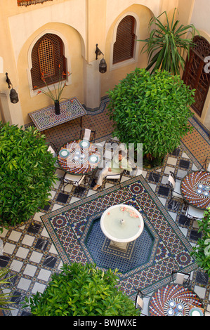 Riad Moussika inn inner courtyard woman well tourism architecture oriental East hotel Old Town Medina Marr Stock Photo