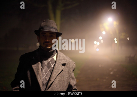 man with trench coat and hat in the park Stock Photo