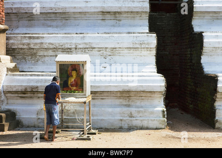 Sinhalese boy praying in front of a Buddha statue in the Mirisawetiya Dagoba, Sacred City, Anuradhapura, Sri Lanka, Asia Stock Photo