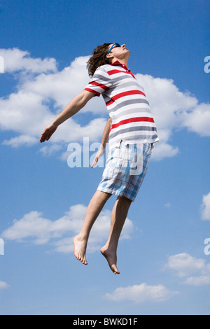 Portrait of energetic man in high jump against bright blue sky Stock Photo