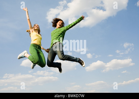 Image of cheerful girl and guy jumping high against bright blue sky and laughing Stock Photo