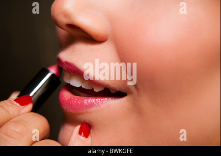 Woman putting on red lipstick Stock Photo