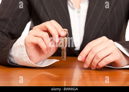 Business woman holds house key for handing over of keys. Isolated on white background. Stock Photo