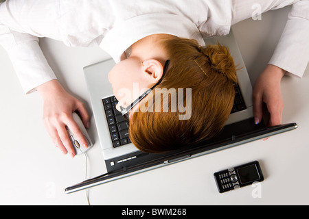 Image of very tired businesswoman or student putting her face on keyboard of laptop