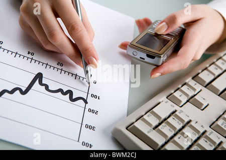 Close-up of female hands holding phone and pen Stock Photo