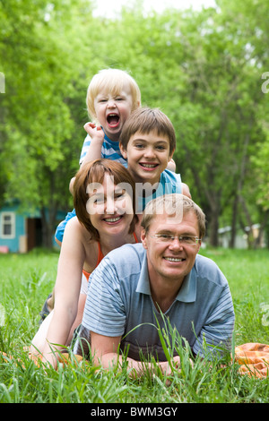 Image of mother, father and two brothers lying on the grass Stock Photo