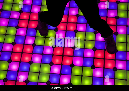 A person dancing on a giant illuminated dancefloor Stock Photo