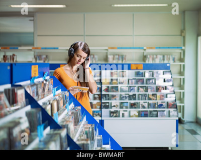 caucasian woman with headphones, choosing cd in music shop. Horizontal shape, front view, waist up, copy space Stock Photo
