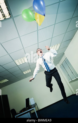businessman flying in office with balloons Stock Photo