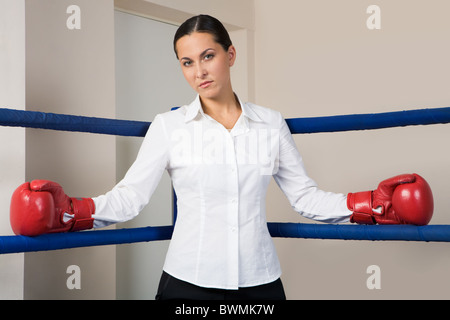 Portrait of strict businesswoman in boxing gloves looking at camera Stock Photo