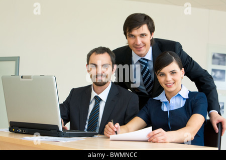 Portrait of several confident colleagues looking at camera with smiles at workplace Stock Photo