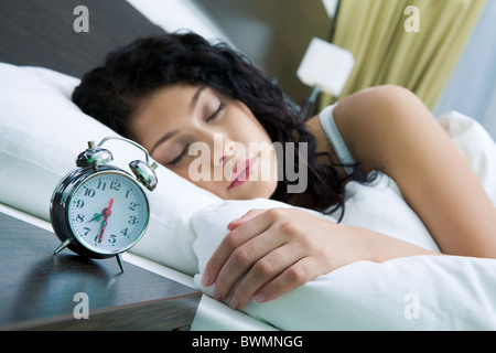 Image of alarm clock on background of sleeping female in the morning Stock Photo