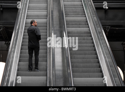 Man ascending on escalator Stock Photo