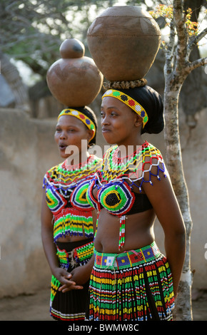 Zulu Girls Wearing Traditional Beaded Dress and Carrying Pots on their Heads, Shakaland Zulu Village, Kwazulu Natal, Africa Stock Photo