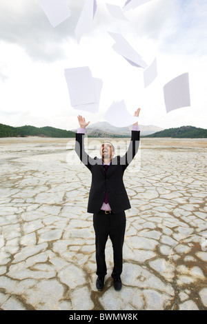 Photo of delighted businessman standing and throwing papers outdoors Stock Photo