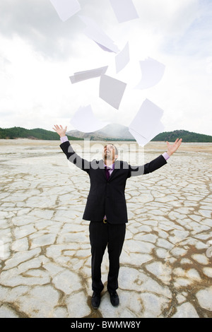 Photo of delighted businessman standing and throwing papers outdoors Stock Photo