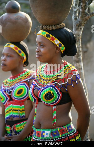 Zulu Girls Wearing Traditional Beaded Dress and Carrying Pots on their Heads, Shakaland Zulu Village, Kwazulu Natal, Africa Stock Photo