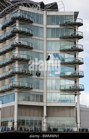 Two men hanging on ropes cleaning windows on highrise St David's Hotel building in Cardiff Bay, Glamorgan, South Wales, UK. Stock Photo