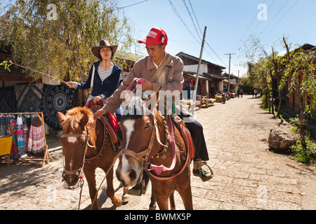 People riding horses in a street in Baisha village, near Lijiang, Yunnan Province, China Stock Photo