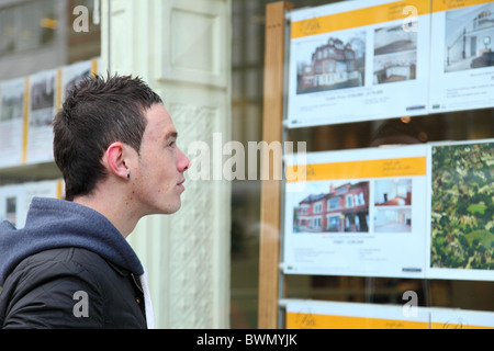 A first time buyer viewing houses in an estate agents window. Stock Photo