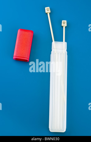 Long plastic red topped knitting needle container and two 4.5 mm needles Stock Photo