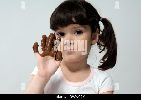 Girl looking at camera, showing her hand full of melted chocolate Stock Photo