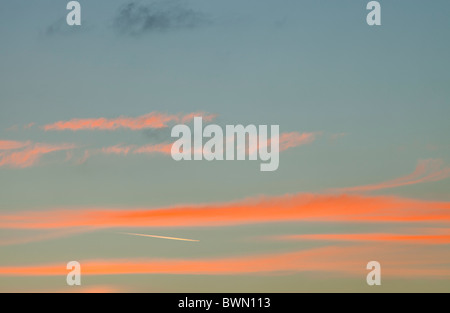 A plane flying through sunset clouds over the Lake District, UK. Stock Photo