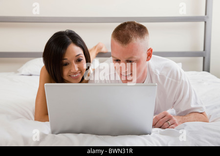 USA, Illinois, Metamora, Young couple lying in bed and using laptop Stock Photo
