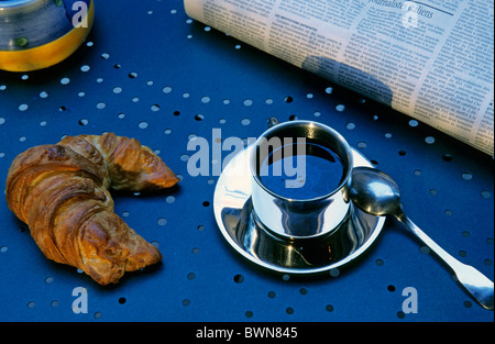 Croissant and coffee cup on a table with the morning newspaper, France. Stock Photo