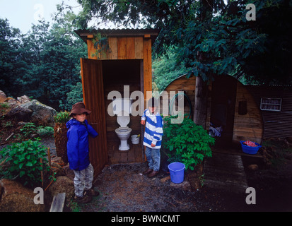 Kids standing next to old family wooden dunny or outhouse in country home backyard in Tasmania Stock Photo