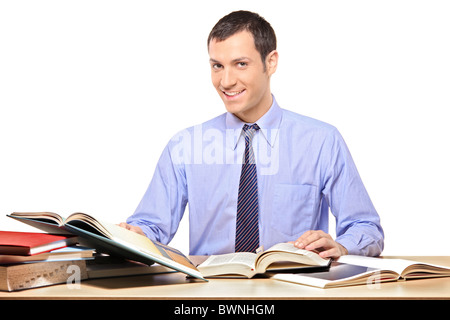 A happy man reading a book, with many other books on the desk Stock Photo