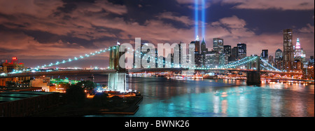 New York City Manhattan skyline with Brooklyn Bridge over Hudson River with reflection at night and skyscrapers and blue beam. Stock Photo