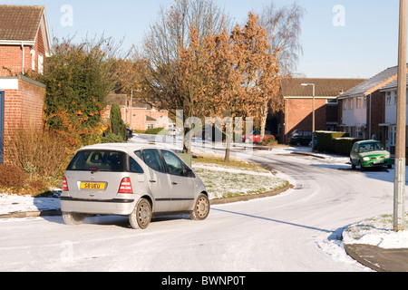 A car driving along an ungritted icy residential road with caution in Nottingham England UK Stock Photo